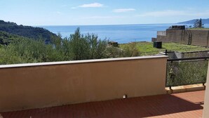 Ein Balkon mit Blick auf das Meer und die Hügel.