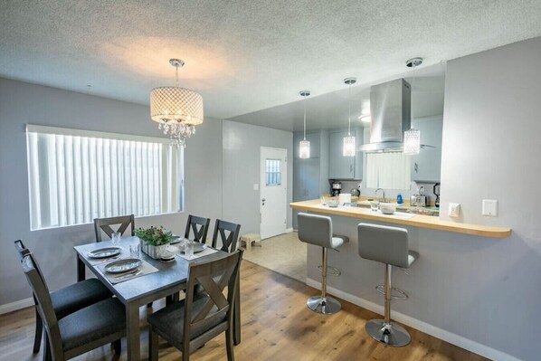 A modern kitchen with a central island, bar stools, and pendant lighting. - Cozy, Calm, Cool 3Bd fenced yard (Monrovia)