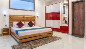 A bedroom with a wooden bed, red wardrobe, and a large window. - The Mountains Retreat (Krishangarh)