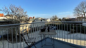 Ein Balkon mit Tisch, Stühlen und einer Topfpflanze.