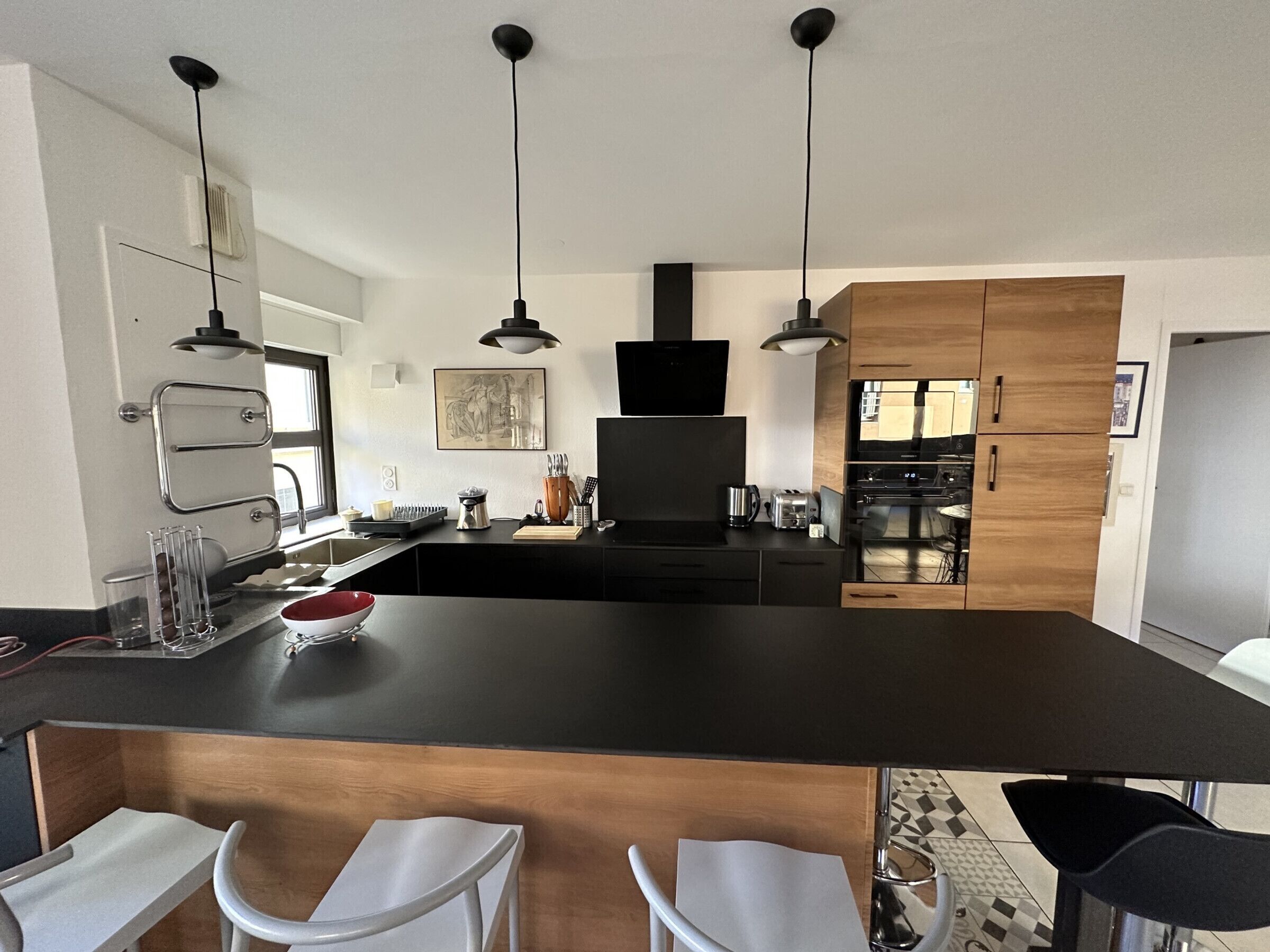 Una cocina moderna con una isla grande, luces colgantes y armarios de madera.