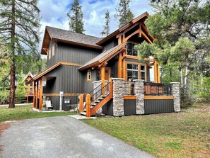 A large, multi-story log cabin with a stone foundation, wooden balconies, and a steeply pitched roof.