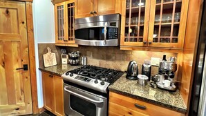 Una cocina con armarios de madera, estufa de acero inoxidable, microondas y cafetera.
