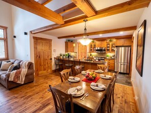 Un coin repas chaleureux avec une table en bois dressée pour quatre personnes, entourée de chaises.