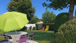 A patio with a table and chairs, a green umbrella, and a slide.