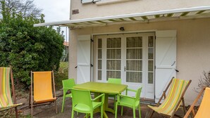 An outdoor patio with a table and chairs, a covered area, and a white door with glass panels.