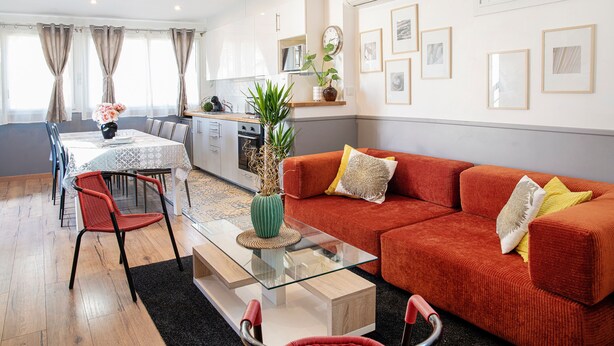 Una sala de estar moderna con una mesa de centro de vidrio, un sofá rojo y un comedor con mesa y sillas.