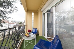 Un balcone con tavolo, sedie e un piccolo giardino.