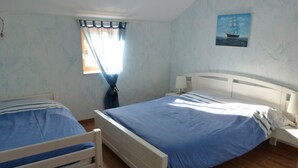 Un dormitorio con dos camas individuales, una ventana con cortinas, un cuadro colgado en la pared y una mesita de noche con lámpara.