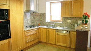 Una cocina con armarios de madera, un lavamanos de acero inoxidable y una ventana con persianas.