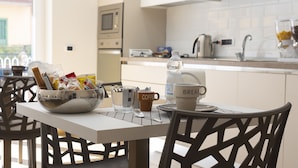 A breakfast table with a bowl of bread and condiments, a coffee cup, a water bottle, and a "BREAKFAST" mug. - MarGab Guest House Yellow Room (Napoli)