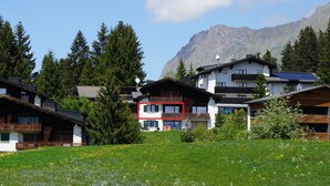 A cluster of traditional alpine houses with balconies, surrounded by lush greenery and a mountain backdrop. - Stgirat Bellaval by Interhome (Valbella)