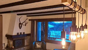 A cozy room with a stone fireplace, a comfortable sofa, and a chair with a deer pillow. - Stgirat Bellaval by Interhome (Valbella)
