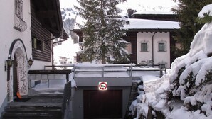A snow-covered entrance with a no parking sign, stone steps, and a view of a tree and buildings in the background. - Stgirat Bellaval by Interhome (Valbella)