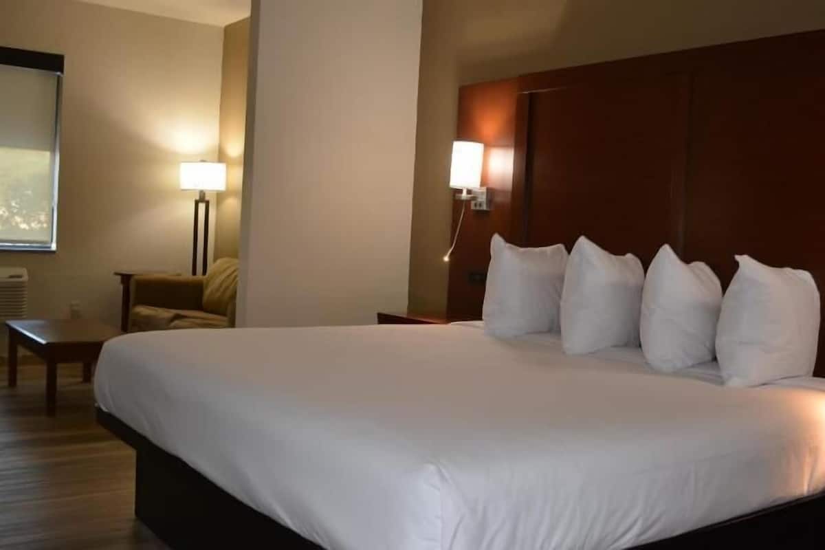 Ein Hotelzimmer mit einem großen Bett, einem Schreibtisch, einem Stuhl, einer Lampe und einem Fenster.