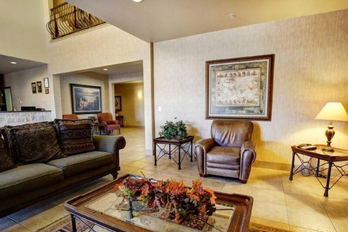 Ein Wohnzimmer mit einer Couch, einem Couchtisch mit Blumenarrangements, einem Ledersessel und einer Lampe.