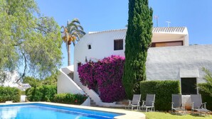 A pool area with lounge chairs and a staircase leading to a white building with purple flowers. - Toscamar by Interhome (Jávea)