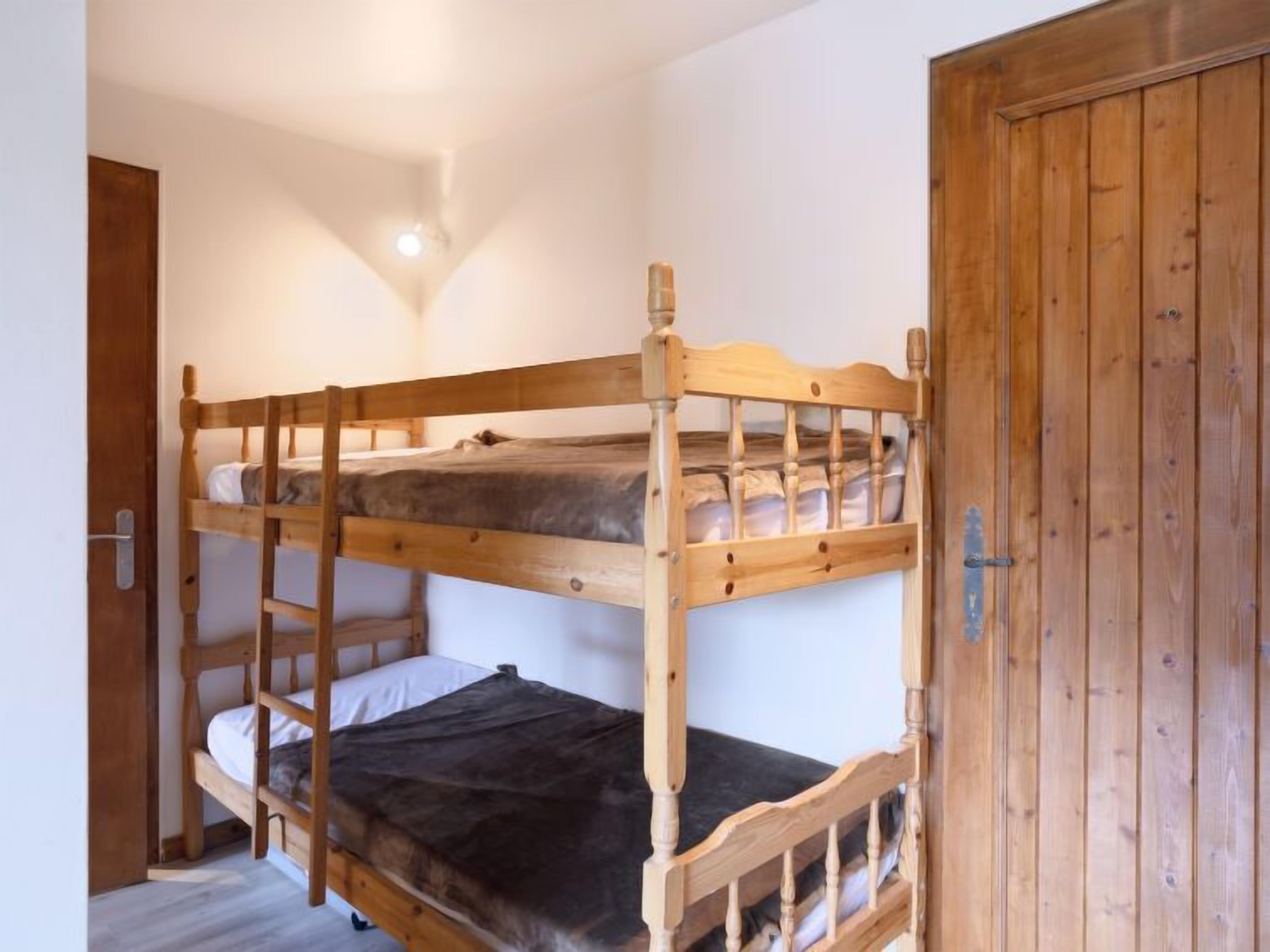 Ein Stockbett in einem Raum mit weißen Wänden und einer Holztür.