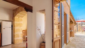 A spacious room with a stone wall, a wooden door, and a tiled floor. - Can Xerret by Interhome (Sencelles)