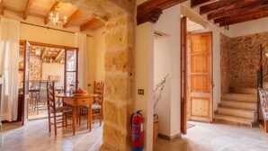 A spacious dining area with a wooden table and chairs, a stone wall, and a staircase leading to an upper level. - Can Xerret by Interhome (Sencelles)