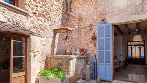 A rustic stone building with a wooden door, a stone water well, and a blue shuttered entrance. - Can Xerret by Interhome (Sencelles)