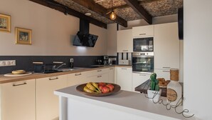 Eine moderne Küche mit weißen Schränken, einer Holz Arbeitsplatte und einer Obstschale.