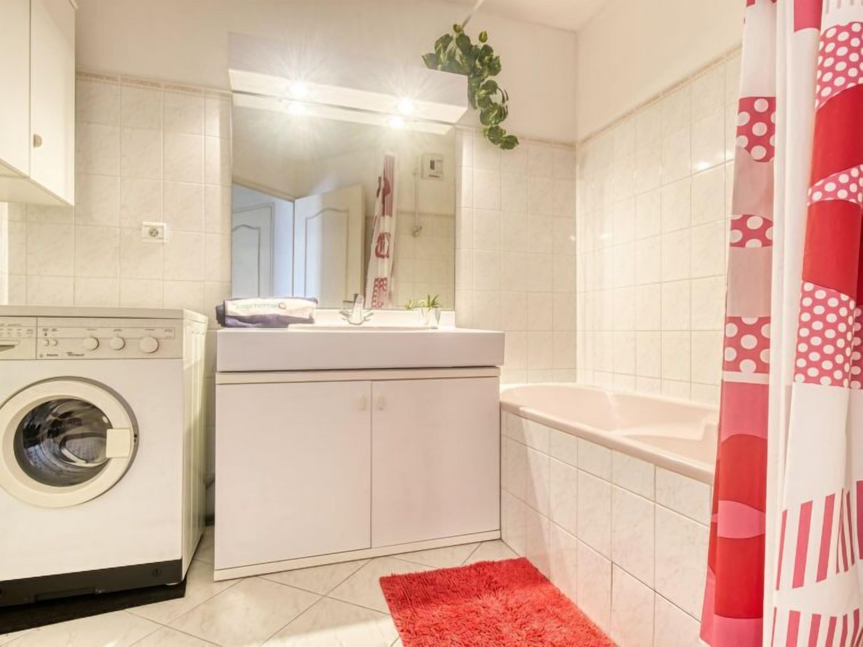 Une salle de bain équipée d’une machine à laver, d’un lavabo et d’une baignoire.