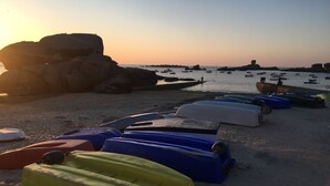 Una spiaggia con kayak e un promontorio roccioso sullo sfondo.