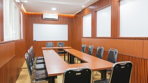 Une salle de conférence équipée d’une longue table, de chaises, d’un écran de projection et d’un appareil de climatisation.