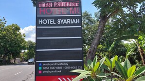 Un panneau d’affichage numérique pour l’hôtel Syariah, affichant les coordonnées et les liens vers les réseaux sociaux.