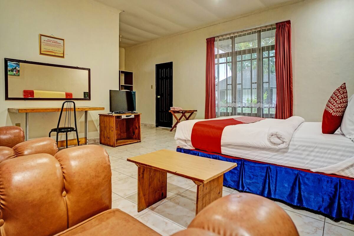 Ein Hotelzimmer mit einem Bett, einem Schreibtisch, einem Fernseher, einem Sessel und einem Sofa.