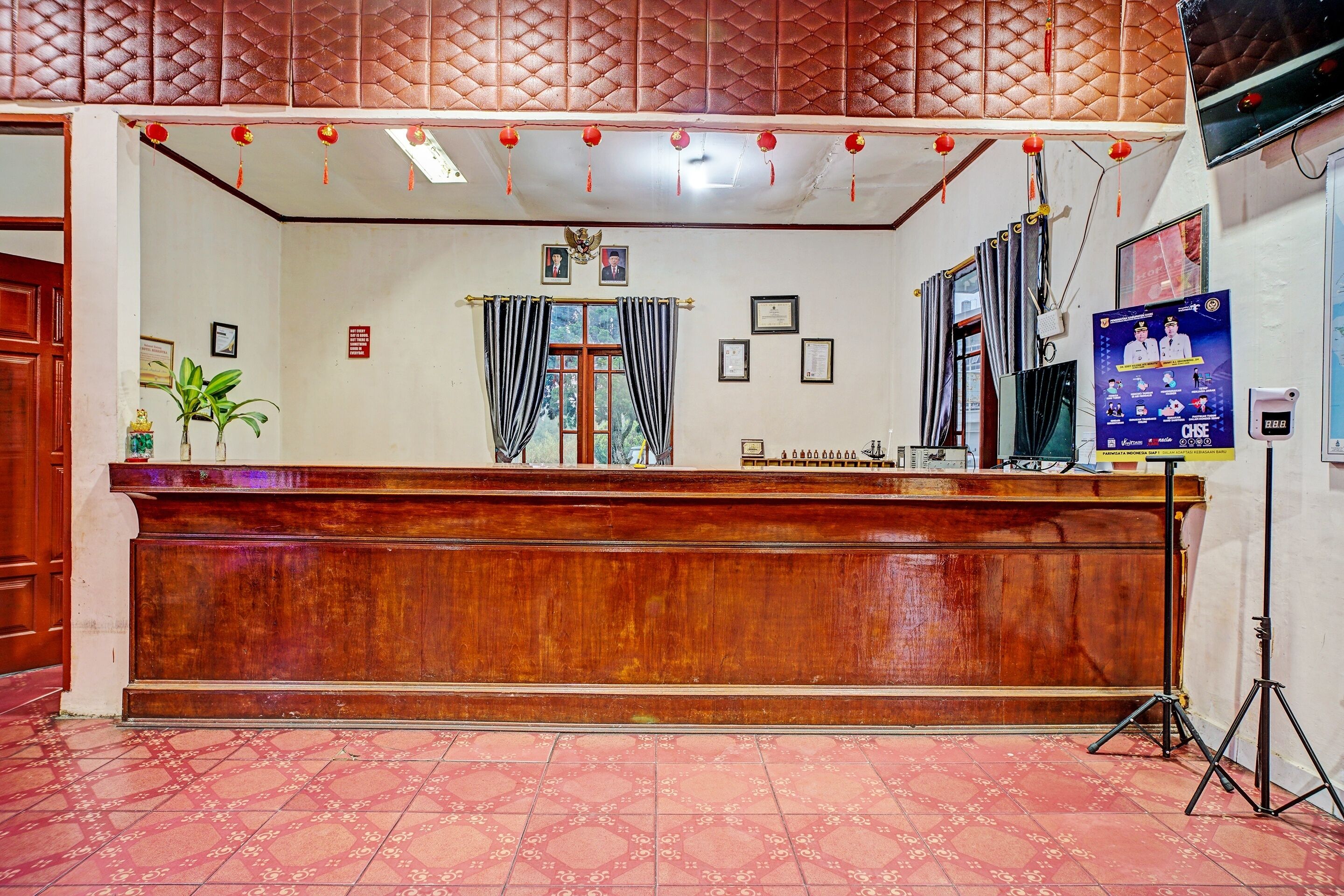 Un área de recepción con mostrador de madera, diplomas enmarcados y un cartel en la pared.