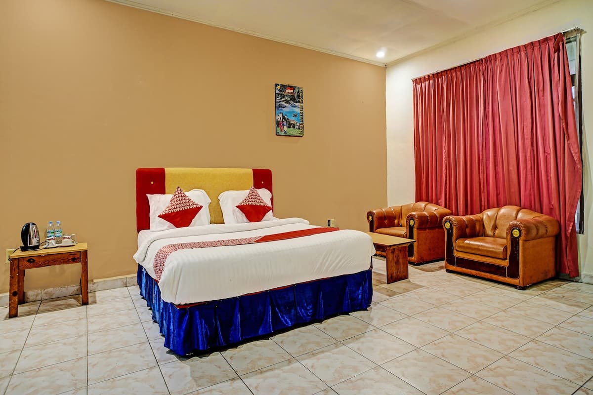 Ein Hotelzimmer mit einem Bett, zwei Sesseln, einem kleinen Tisch und einem Nachttisch.