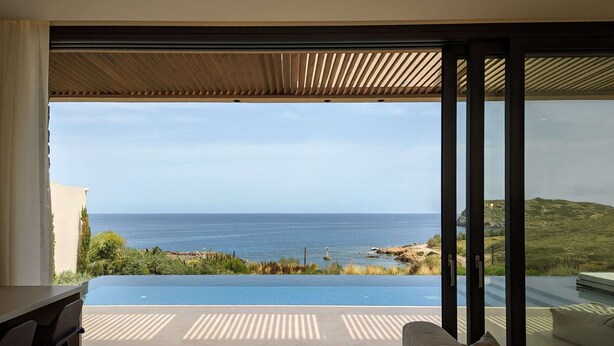 Ein modernes Zimmer mit einer großen Schiebeglasdoor, die zu einem privaten Infinity-Pool mit Meerblick führt.