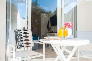 A white table with two orange drinks and a pink flower vase. - Acrotel Lilyann Boutique Hotel (Sithonia)