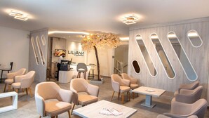 A modern interior with seating areas, a reception desk, and a decorative tree. - Acrotel Lilyann Boutique Hotel (Sithonia)