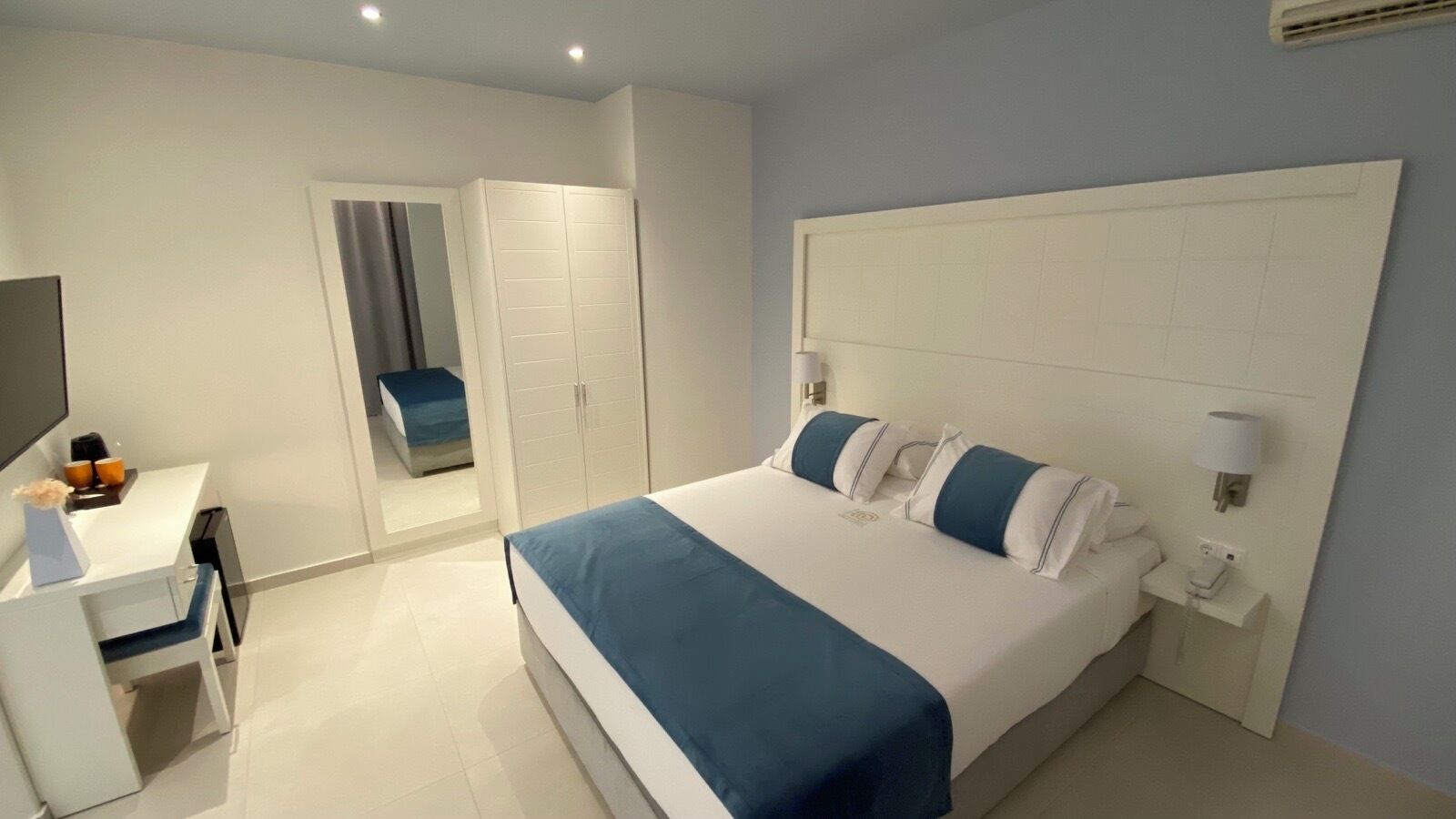 Ein modernes Hotelzimmer mit einem großen Bett, einem Schreibtisch und einem Kleiderschrank.