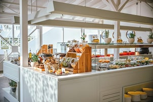 Monipuolinen aamiaisbuffet, jossa on tarjolla erilaisia ruokia, lasipurkkeja ja kahvilaitteita.