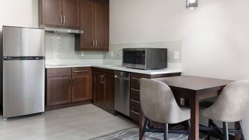 Una cocina moderna con armarios de madera, electrodomésticos de acero inoxidable y una zona de comedor con dos sillas.