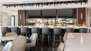 A modern bar area with a long counter, multiple bar stools, and a seating area with a table and chairs. - Residence Inn by Marriott Anaheim Brea (Brea)