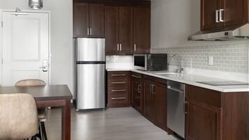 A modern kitchen with dark wooden cabinets, stainless steel appliances, and a white countertop.