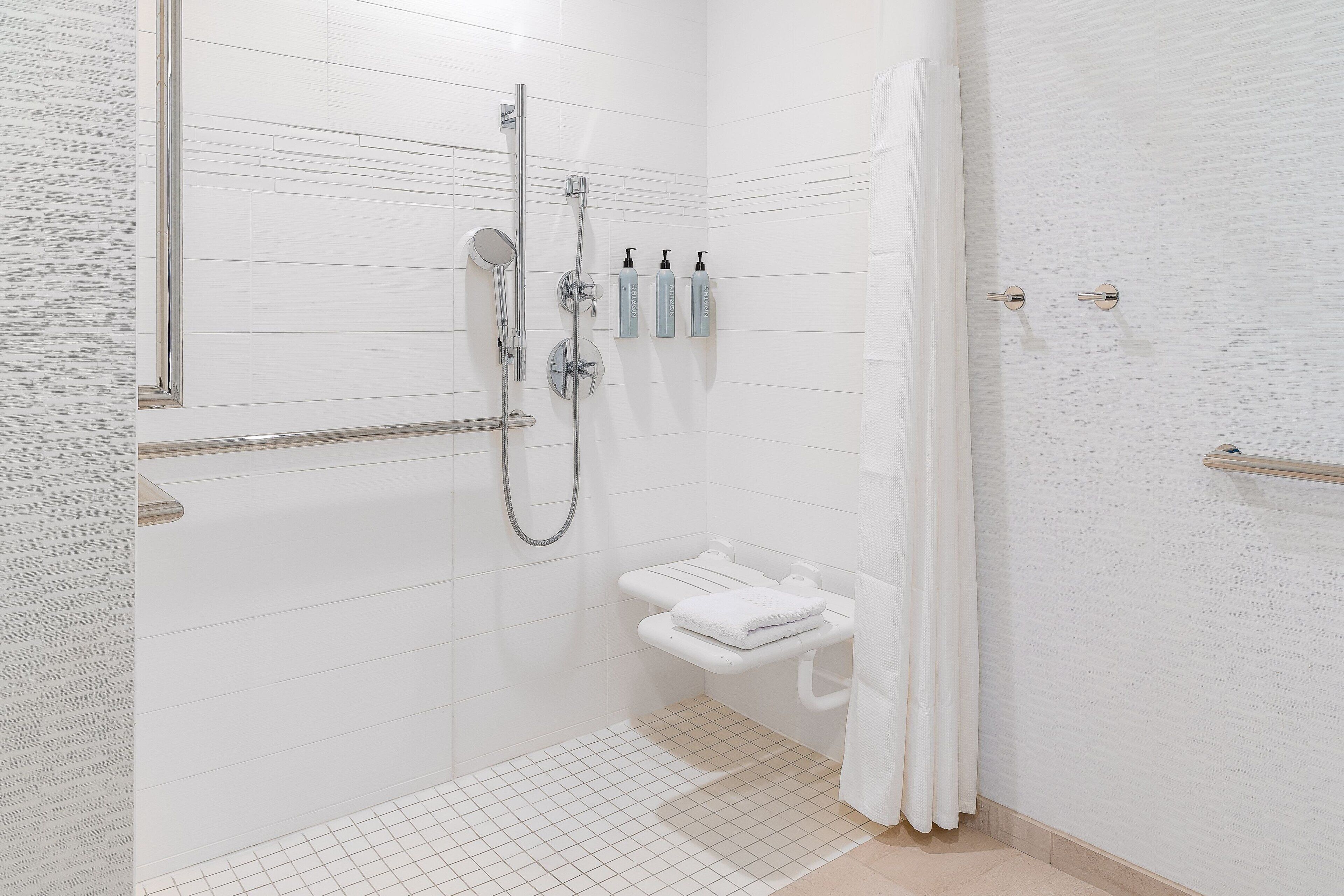 Un bagno moderno con doccia a filo pavimento, un water con portasci e un asciugamani ad aria.