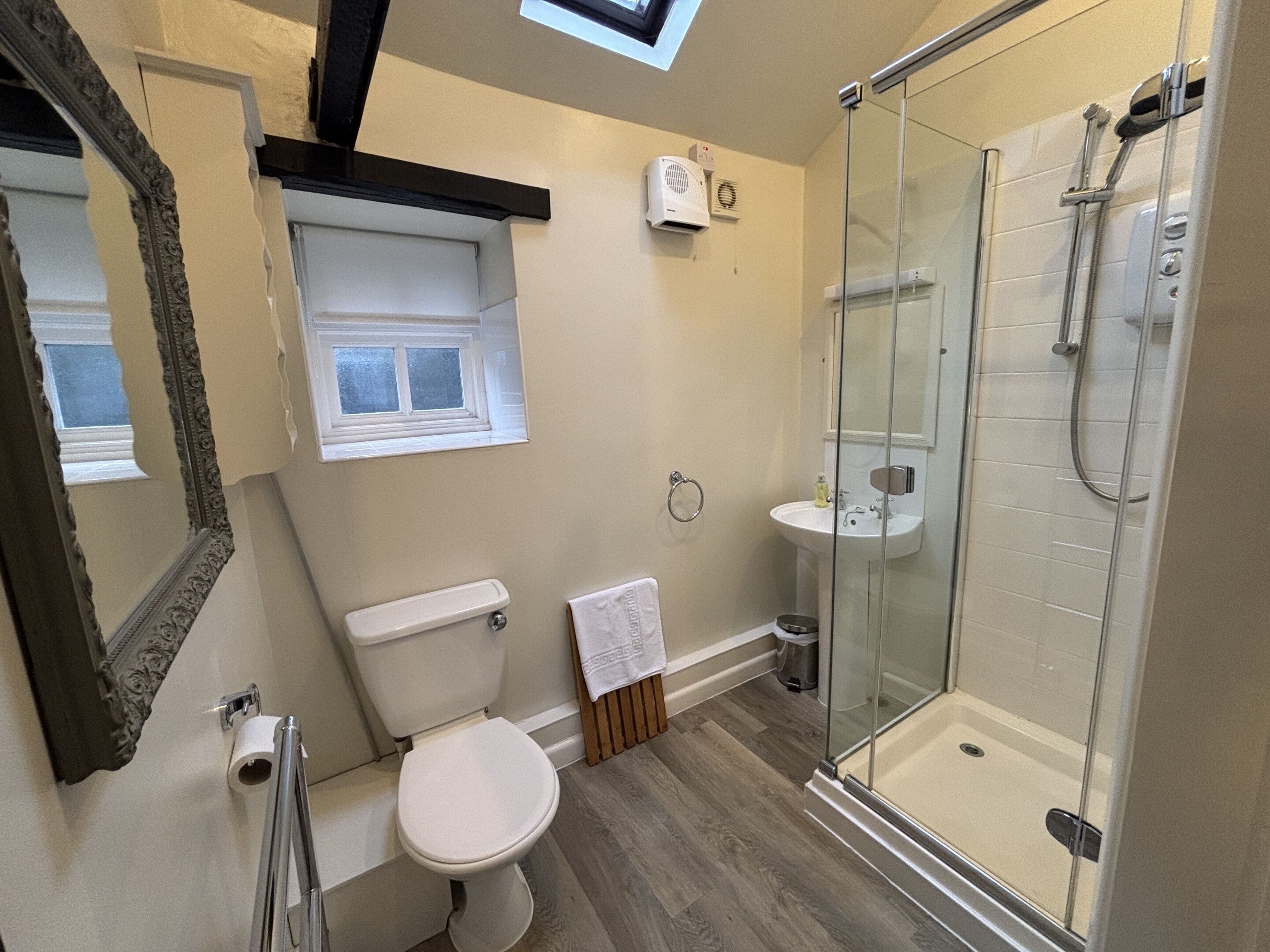 A modern bathroom with a glass shower enclosure, a toilet, a sink, and a window.