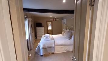 A bedroom with a bed, a dresser, a mirror, and a nightstand.