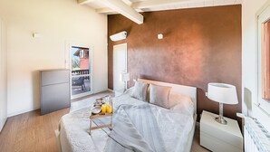 Un dormitorio con cama, mesita de noche, lámpara y una pequeña mesa con cosas para el desayuno.