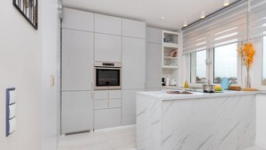 Una cocina moderna con electrodomésticos integrados, una isla de mármol y vistas a la ciudad a través de amplios ventanales.