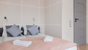 Una habitación de hotel moderna con una cama grande, dos mesitas de noche y una puerta.