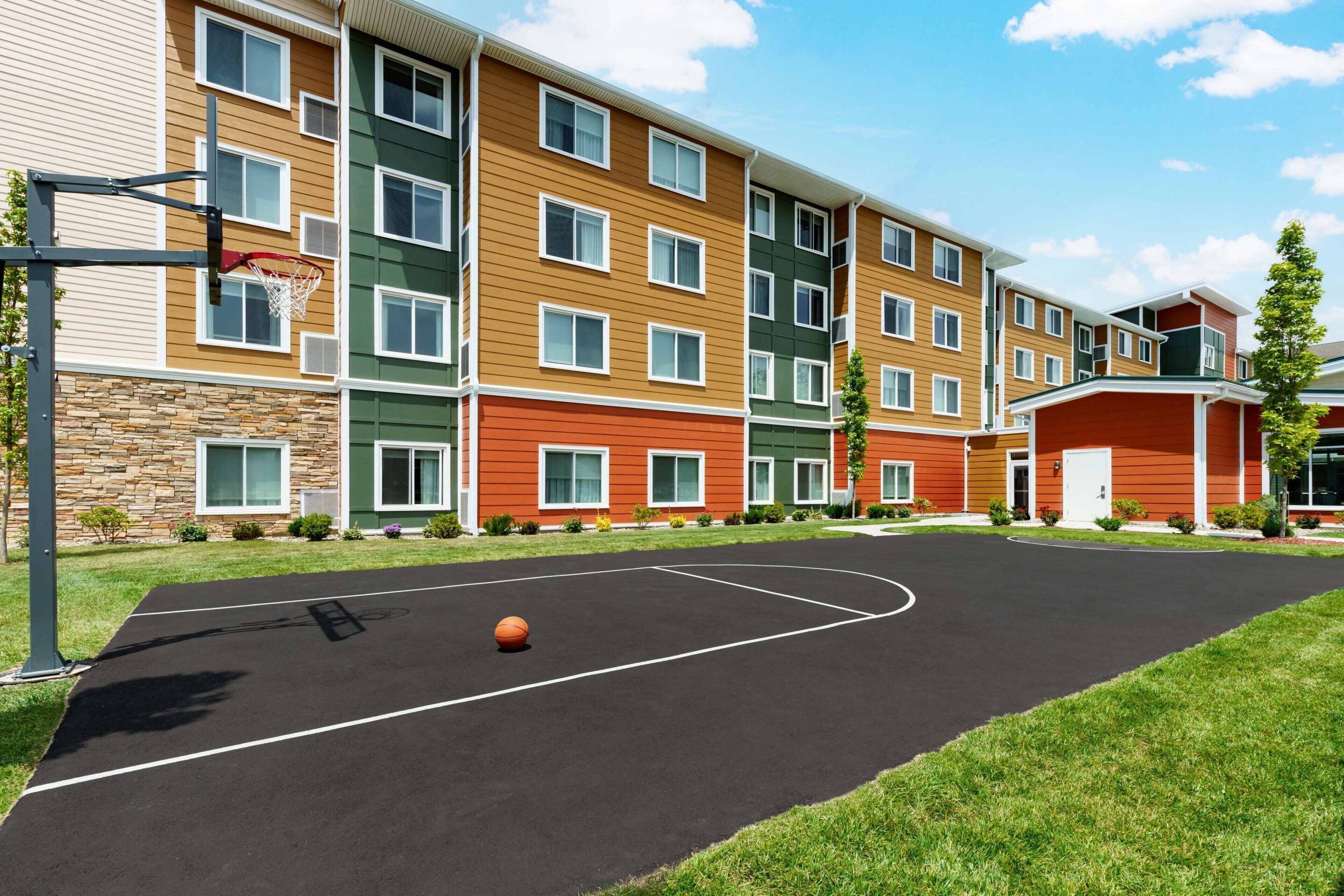 A multi-story building with a basketball court in front.