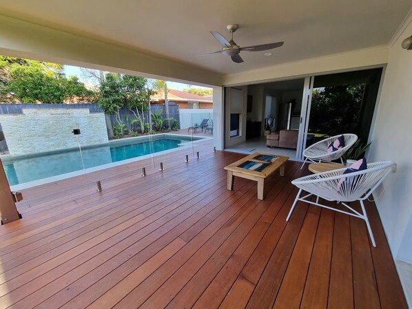 Relax by the pool in this serene outdoor space, featuring a deck, pool, and comfortable seating area.