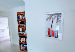 Cozy reading nook with a bookshelf and artwork featuring surfboards and palm trees.